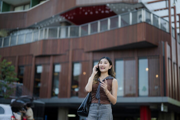 Fototapeta premium Woman smiling talking on phone in modern city street