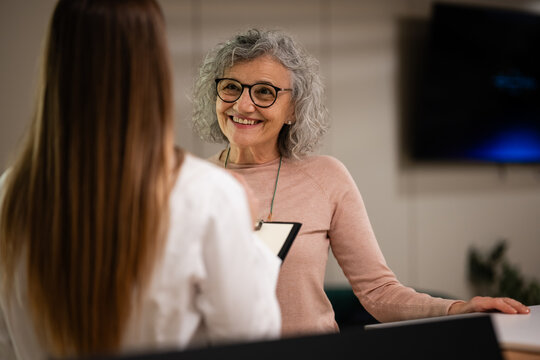 Senior woman smiling offering customer service at reception