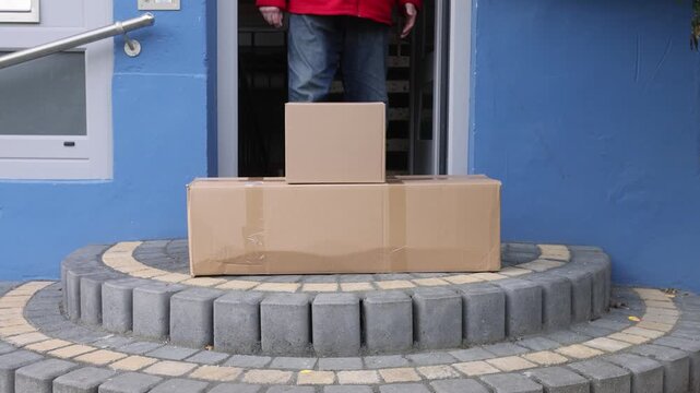 Delivery man leaving cardboard boxes at house door