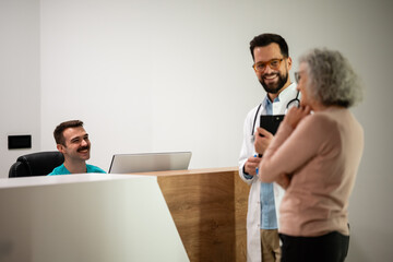Doctor consulting senior patient at clinic reception