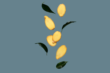 Obraz premium Flying slices of fresh ginger root and leaves on blue background