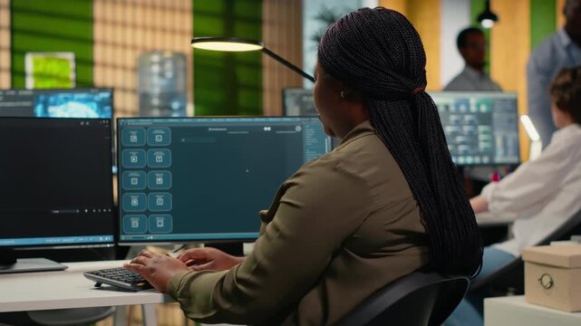 Software developer in office solving tasks with AI LLM chatbot answering prompts. Tech agency system administrator using PC to interact with large language model program, camera B