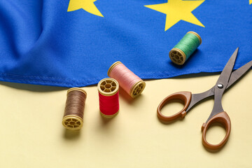 Scissors, threads and flag of European Union on yellow background