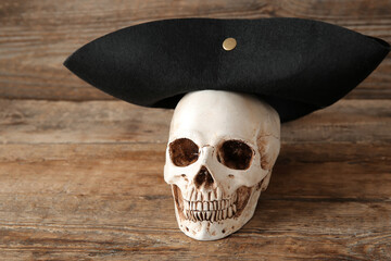 Human skull with pirate hat on brown wooden background