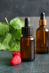 Bottles of cosmetic raspberry oil on dark background