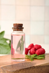 Bottle of cosmetic raspberry oil on white background, closeup
