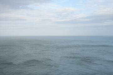 Peaceful nature background in shades of blue, calm sea and pastel sky with clouds
