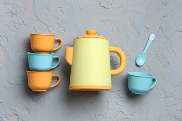 Teapot with cups and spoon for baby on grunge grey background