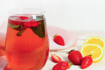 Glass of tasty strawberry juice on white table