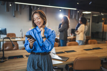 Professional woman smiling using smart phone in modern office