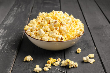 Bowl with crispy popcorn on dark wooden background