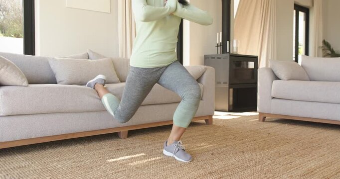 Right foot lifting onto sofa triggers woman performing split squats in living room adding leg power