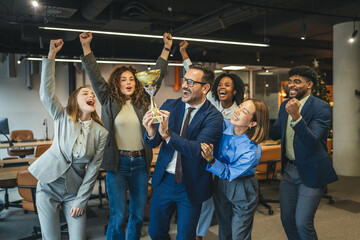 Diverse business team celebrating achievement and success holding trophy