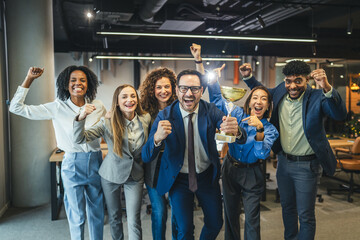 Fototapeta premium Diverse business team celebrating achievement and success holding trophy