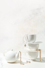 Tea set with stylish jewelry on white table