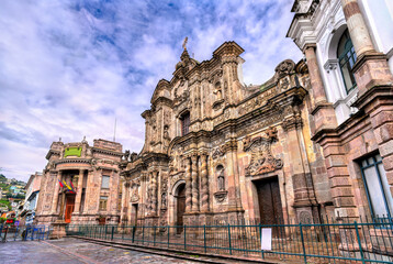 Ornate stone facade of La Compania de Jesus church stands in historic center of Quito, Ecuador. Baroque architecture features intricate carvings and Solomonic columns in UNESCO World Heritage site