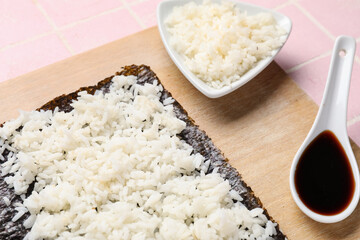 Wooden board of nori with rice and sauce on table, closeup