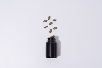 Black Plastic Supplement Bottle with Floating Pills &ndash; Minimal Healthcare Concept