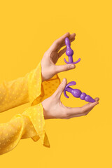 Fototapeta premium Woman with anal plugs from sex shop on yellow background