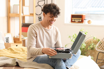 Young man with record player in bedroom