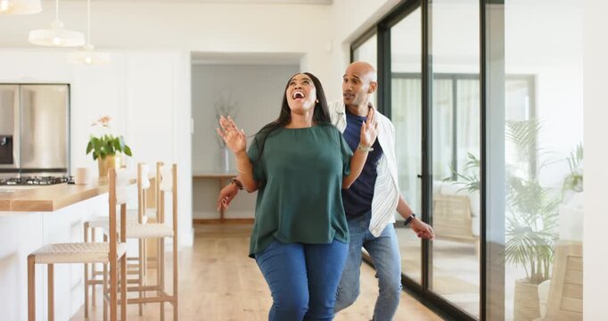 African American couple entering sliding glass door and marking entry with dance on hardwood floor