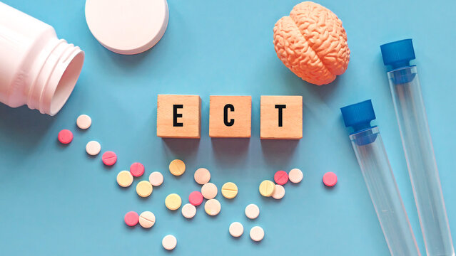 Wooden Blocks Spelling "ECT" Acronym Next to Model Brain, Pills, and Medicine Bottle for Electroconvulsive Therapy Concept