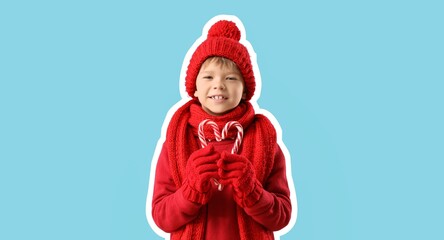 Boy in warm red sweater, scarf and winter hat, with candy canes on blue background