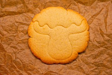 Golden reindeer shaped Christmas cookie on warm rustic baking paper