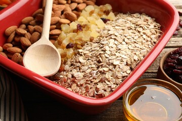 Making granola. Oat flakes, dried fruits, almond nuts and honey on wooden table, closeup