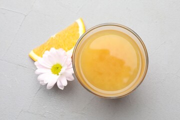 Fresh orange juice in glass, fruit slice and flower on light table, top view