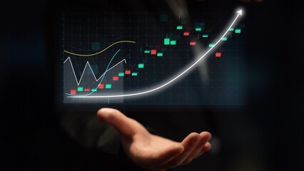 A hand extends towards a digital screen displaying a stock market graph, featuring colorful candlesticks and curves that indicate growth and financial trends. Copula