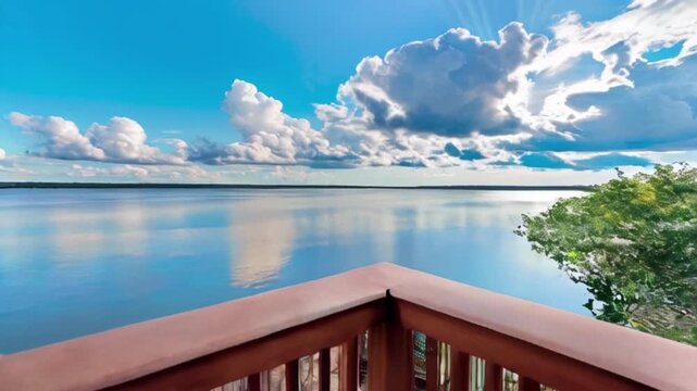 a wooden deck or porch with a railing, overlooking a calm body of water under a blue sky created with generative ai