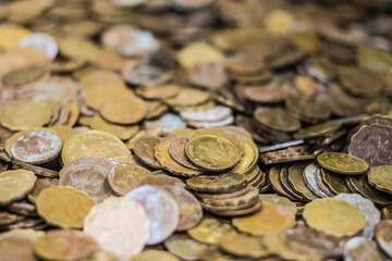 A pile of assorted coins of various sizes and colors, many showing signs of wear, suggesting a collection of old or foreign currency.