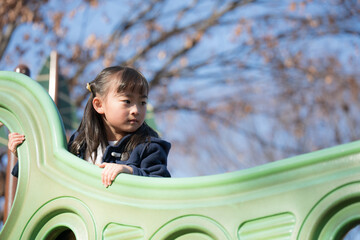 秋の公園で遊具で遊ぶ子供　冬の子どもお出かけやレジャーのイメージ