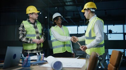 Multiracial engineers and architect reviewing blueprints at a project site while wearing safety gear during daytime in an office setting - Powered by Adobe