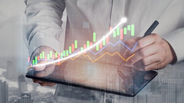 A business professional holds a tablet displaying colorful financial graphs and data analysis representing growth and trends in a modern office setting. Copula - Powered by Adobe