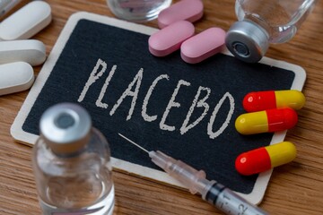 A chalkboard with the word "PLACEBO" surrounded by various pills, capsules, and a syringe. Medical research, clinical trials, and the placebo effect concept.