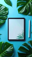Tablet, stylus, and leaves on blue background