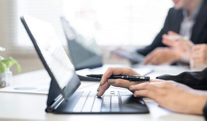 Close-up of a businesswoman or student hands typing on a laptop keyboard during a meeting, class, or work session in an office environment.