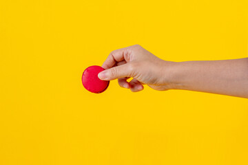 Red macarons in hand on yellow background