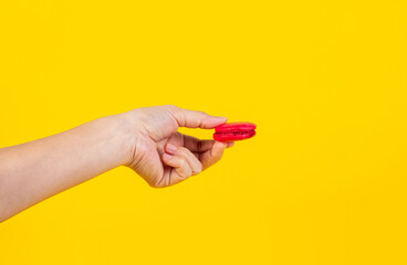 Red macarons in hand on yellow background