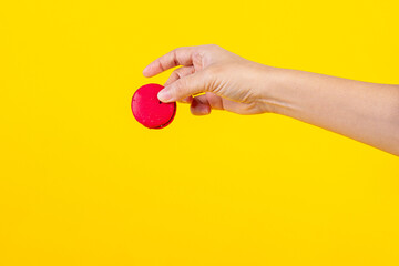 Red macarons in hand on yellow background