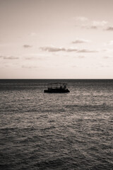 Black and white portrait of a boat in the middle of the sea.
