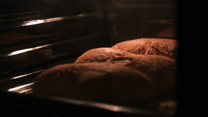 Three loaves of bread in the oven in a dark room. Homemade bread baking.
