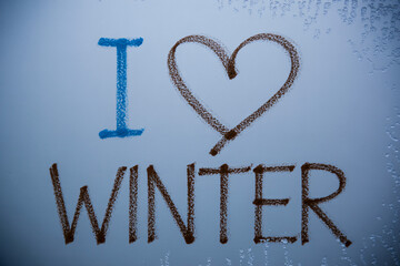 I love winter message written on a frosty window pane with a heart shape and condensation creating a cozy seasonal feeling indoors.