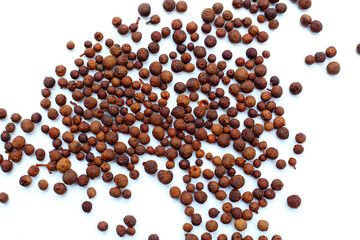 A heap of dark-brown, aromatic allspice berries on a white background.