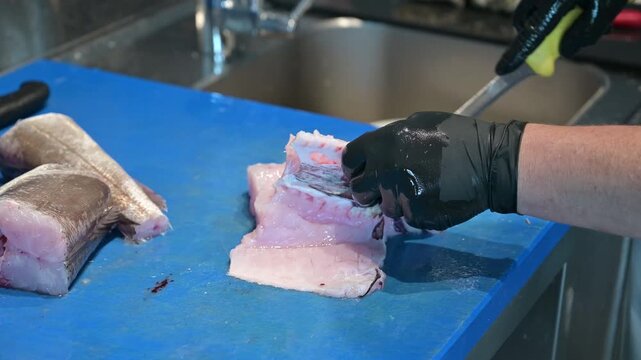 pescivendolo pulisce un merluzzo sul bancone della pescheria