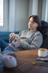 Feminine hipster man crochet handmade use hook knitting needles and wool yarn relaxing on couch