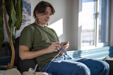 Hipster creative man crochet handmade use knitting supplies hook and wool yarn on couch at home