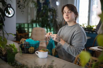 Feminine hipster man crochet handmade use hook knitting needles and wool yarn relaxing on couch